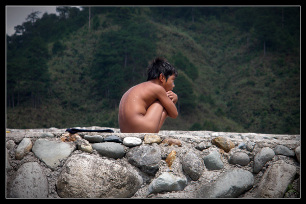 A kid drying off on top of a flood control after a swim at Chico River.
